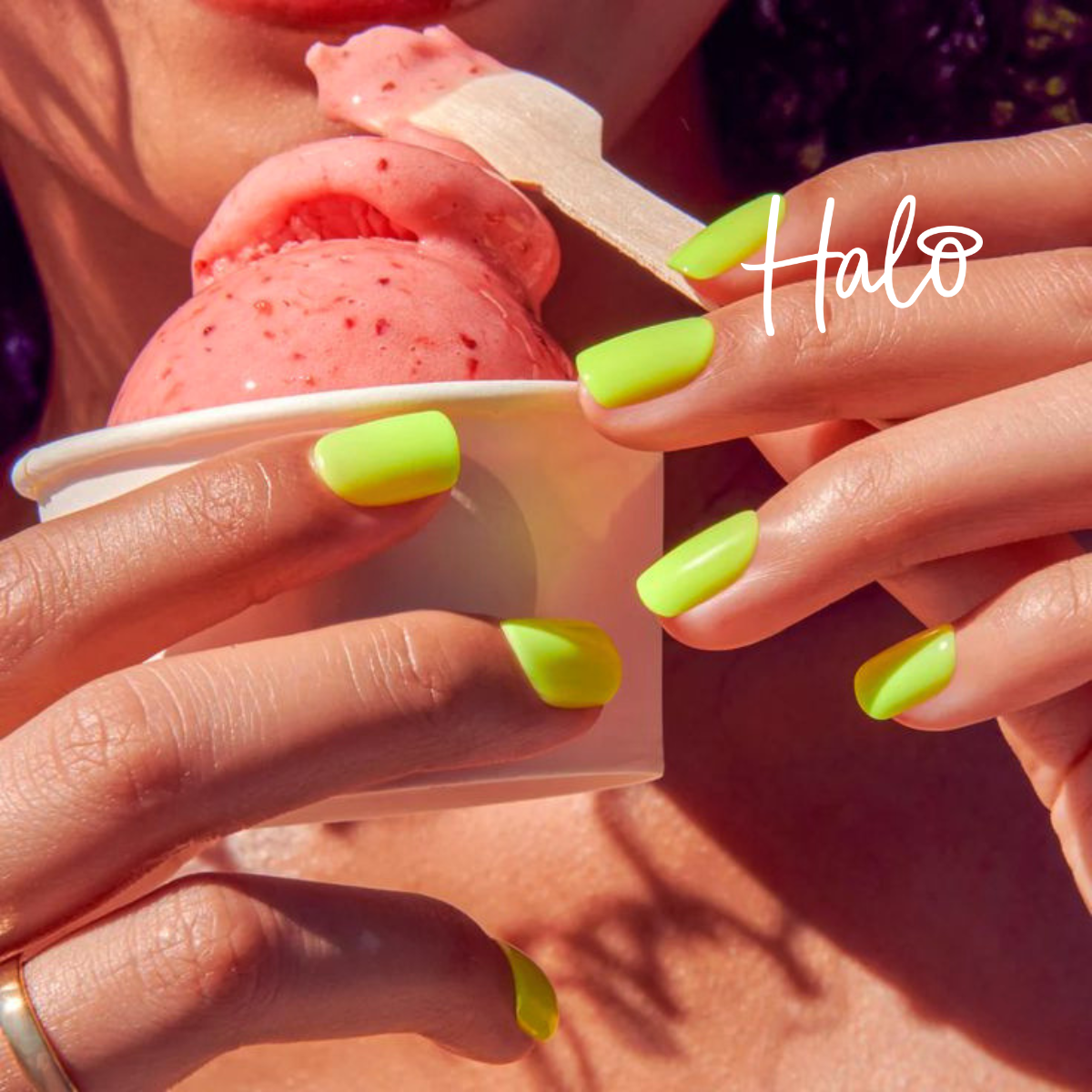 Bright neon yellow-green soft square nails holding a cup of pink ice cream outdoors, showcasing a vibrant summer manicure by Halo Gel Polish.