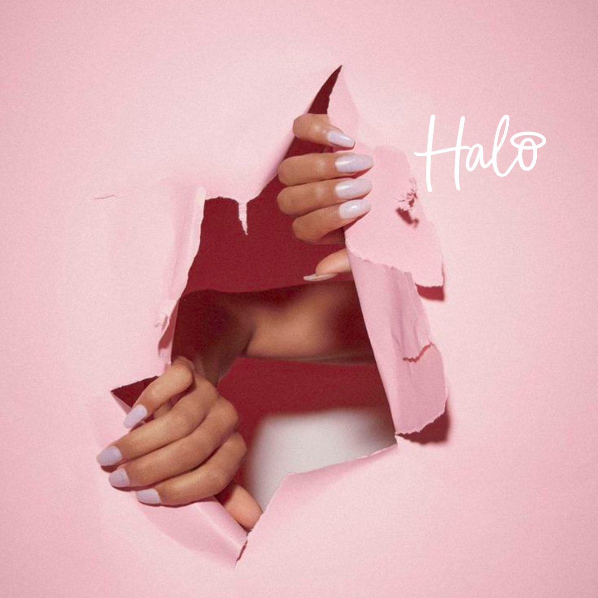 wo hands with long almond-shaped nails in a soft lilac manicure reach through torn pink paper, creating a striking beauty campaign image with the Halo logo displayed in the top right.