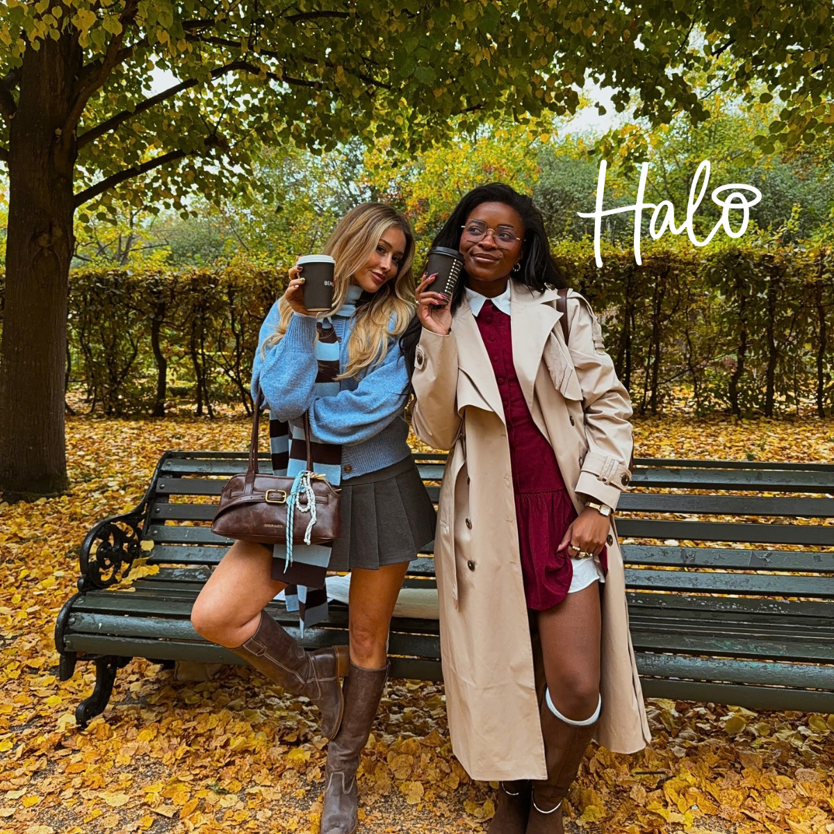 Two women holding coffee cups in an autumn park, wearing seasonal outfits surrounded by golden leaves.