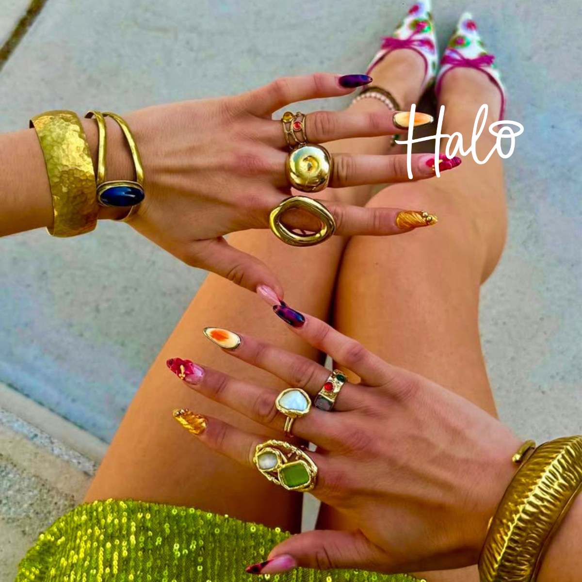 Colourful European summer-inspired nail art featuring abstract fruit, shell and sunset designs on almond-shaped nails, styled with chunky gold jewellery and vibrant accessories.