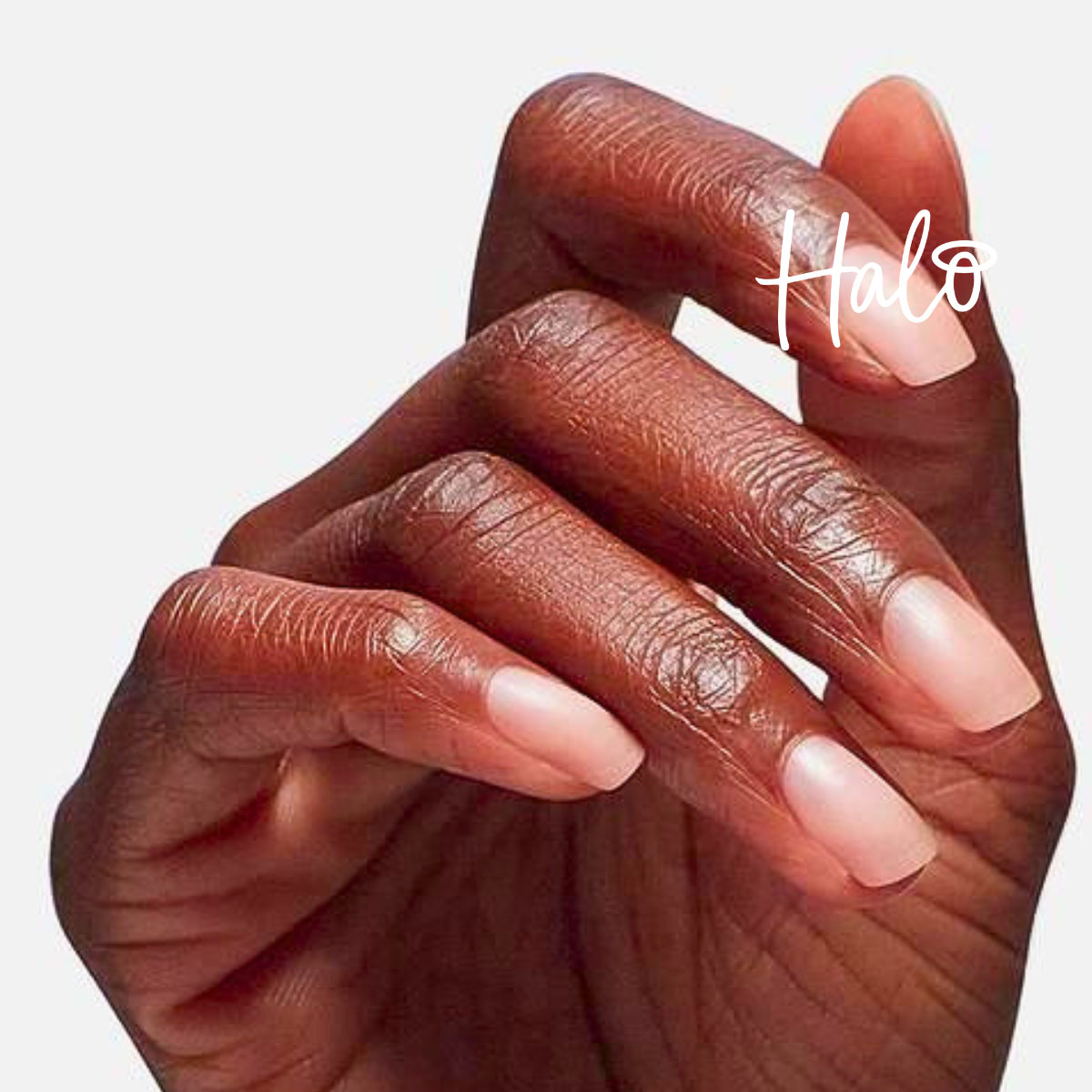 Close-up of a hand with square-shaped nails featuring a soft nude-pink ombré manicure, with the Halo logo overlaid.
