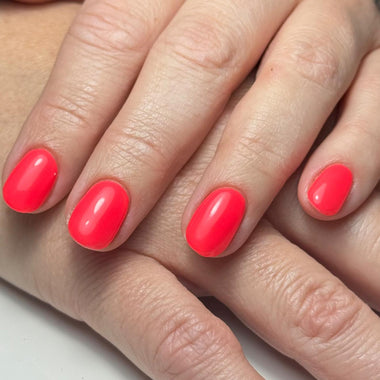 Close-up of hands with bright red nail polish on a neutral background