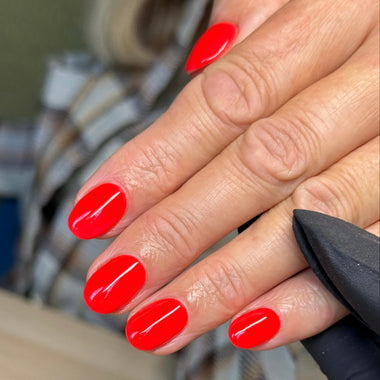 Close-up of hands with red nail polish against a blurred background