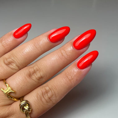 Hand with red nail polish on a neutral background