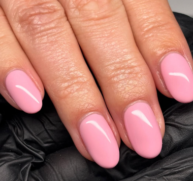 Close-up of hands with pink nail polish on a black background
