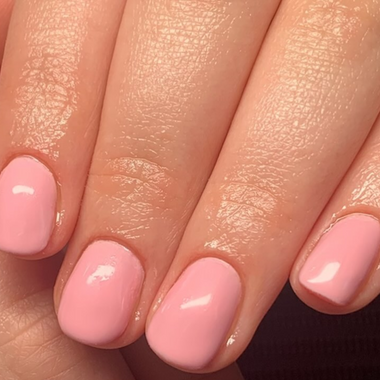 Close-up of a hand with pink nail polish on a neutral background