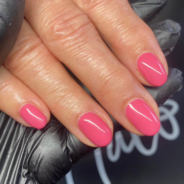 Hand with pink nail polish wearing a black glove against a dark background
