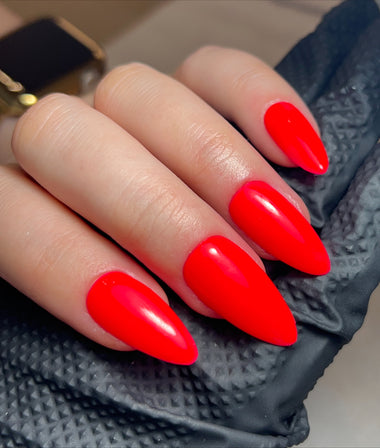 Hand with bright red nail polish on a textured black surface