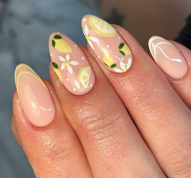 Nail art with lemon and flower designs on a light pink background