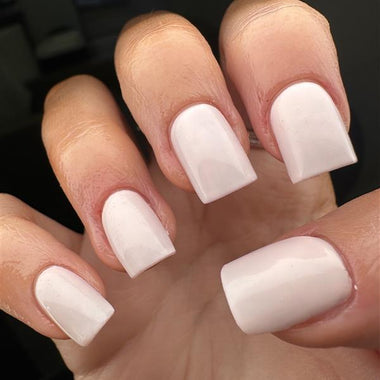 Close-up of a hand with white nail polish on a blurred background