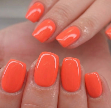 Close-up of a hand with bright orange nail polish on a neutral background