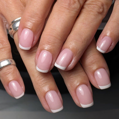 Close-up of hands with pink nail polish on a dark background