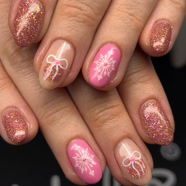 Close-up of hands with pink and glittery nail design on a blurred background