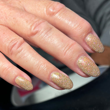 Close-up of a hand with glittery gold nail polish.