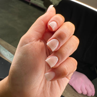 Close-up of a hand with neatly manicured nails in a neutral color.
