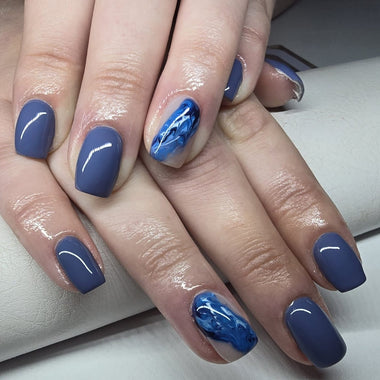 Close-up of hands with blue nail polish on a white background