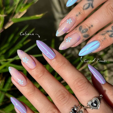 Nail art with floral designs on a hand against a green leafy background