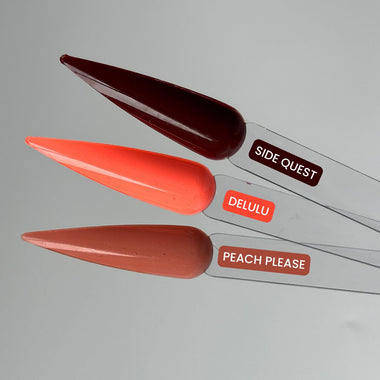 Three nail art tips with labels 'SIDE QUEST', 'DELULU', and 'PEACH PLEASE' on a gray background.
