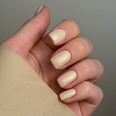 Hand with beige nail polish on a neutral background