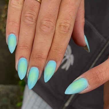 Close-up of a hand with teal and green gradient nail polish.