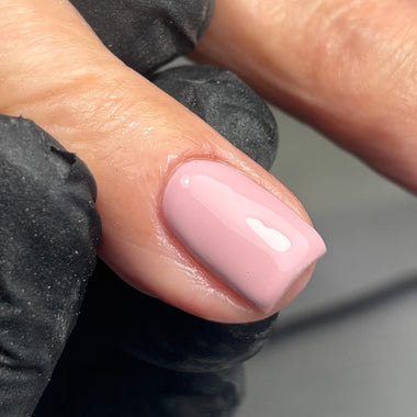 Close-up of a hand with a pink nail and black glove on a neutral background