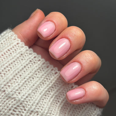 Close-up of a hand with pink nail polish wearing a textured beige sweater.