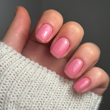 Close-up of a hand with pink nails wearing a white textured sleeve.