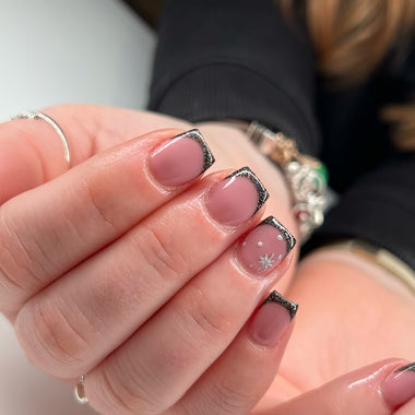Close-up of a hand with pink nail polish and decorative elements.