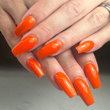 Close-up of a hand with bright orange nail polish on a neutral background