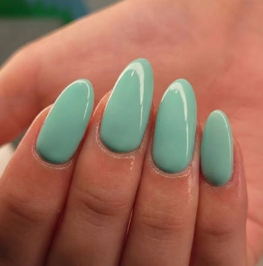 Hand with light green nail polish on a blurred background