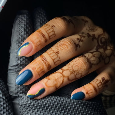 Hand with blue nail polish and henna design on a dark background