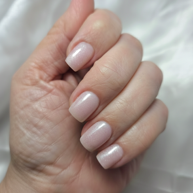 Close-up of a hand with light pink nail polish on a white background