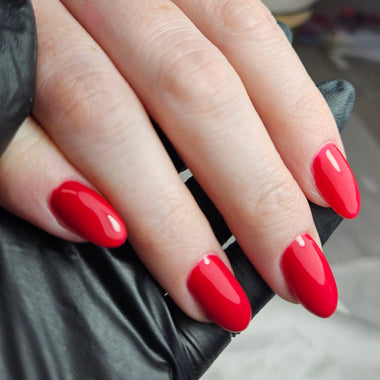 Hand with red nail polish wearing a silver ring on a blurred background