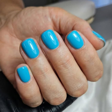 Hand with blue nail polish on a blurred background