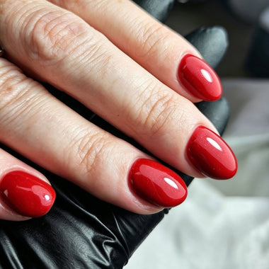 Close-up of a hand with red nail polish wearing a black glove.
