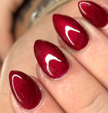 Close-up of a hand with red nail polish and white crescent moon designs.