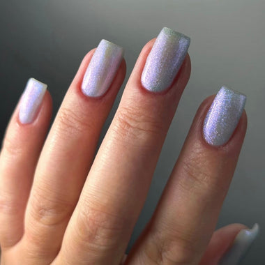 Close-up of a hand with glittery silver blue nail polish on a neutral background