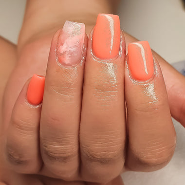 Close-up of a hand with orange-pink nail polish on a neutral background