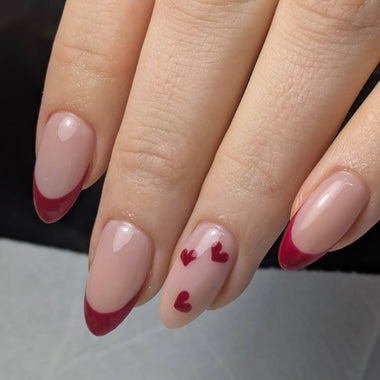 Close-up of a hand with pink and red nail design on a neutral background