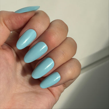 Hand with light blue nail polish on a neutral background