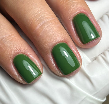 Close-up of a hand with green nail polish on a white background