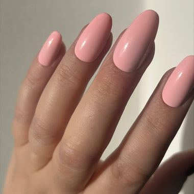 Hand with pink nail polish on a neutral background