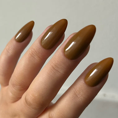 Hand with brown nail polish on a plain background