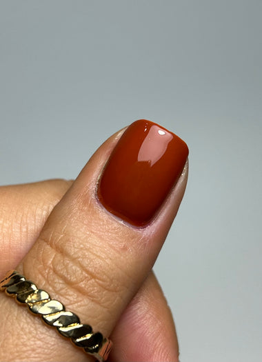 Nail with brown polish on a neutral background