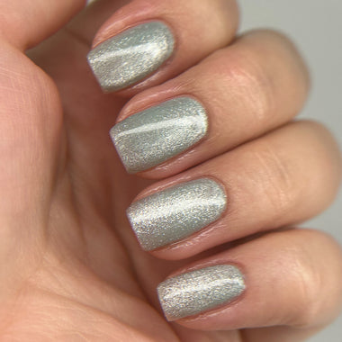 Hand with silver glittery nail polish on a neutral background