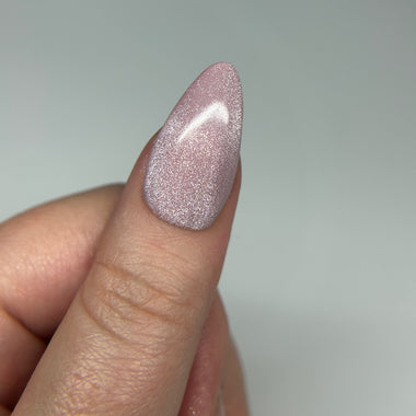 Close-up of a hand with a glittery pink nail on a plain background