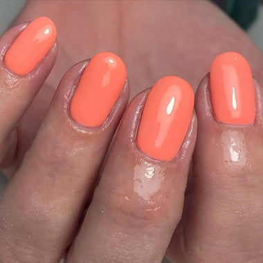 Close-up of a hand with bright orange nail polish on a neutral background