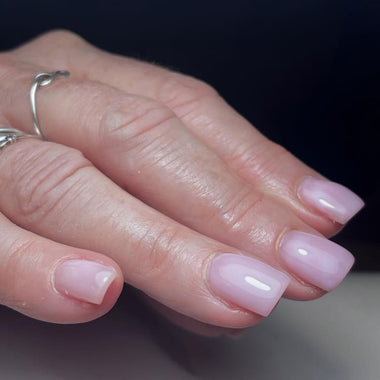 Close-up of a hand with pink nail polish on a dark background