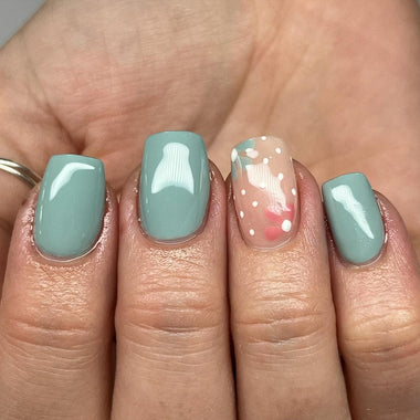 Close up of short square nails with blue nail polish and floral nail art