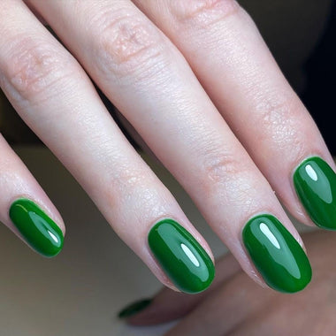 Close-up of hands with green nail polish on a neutral background